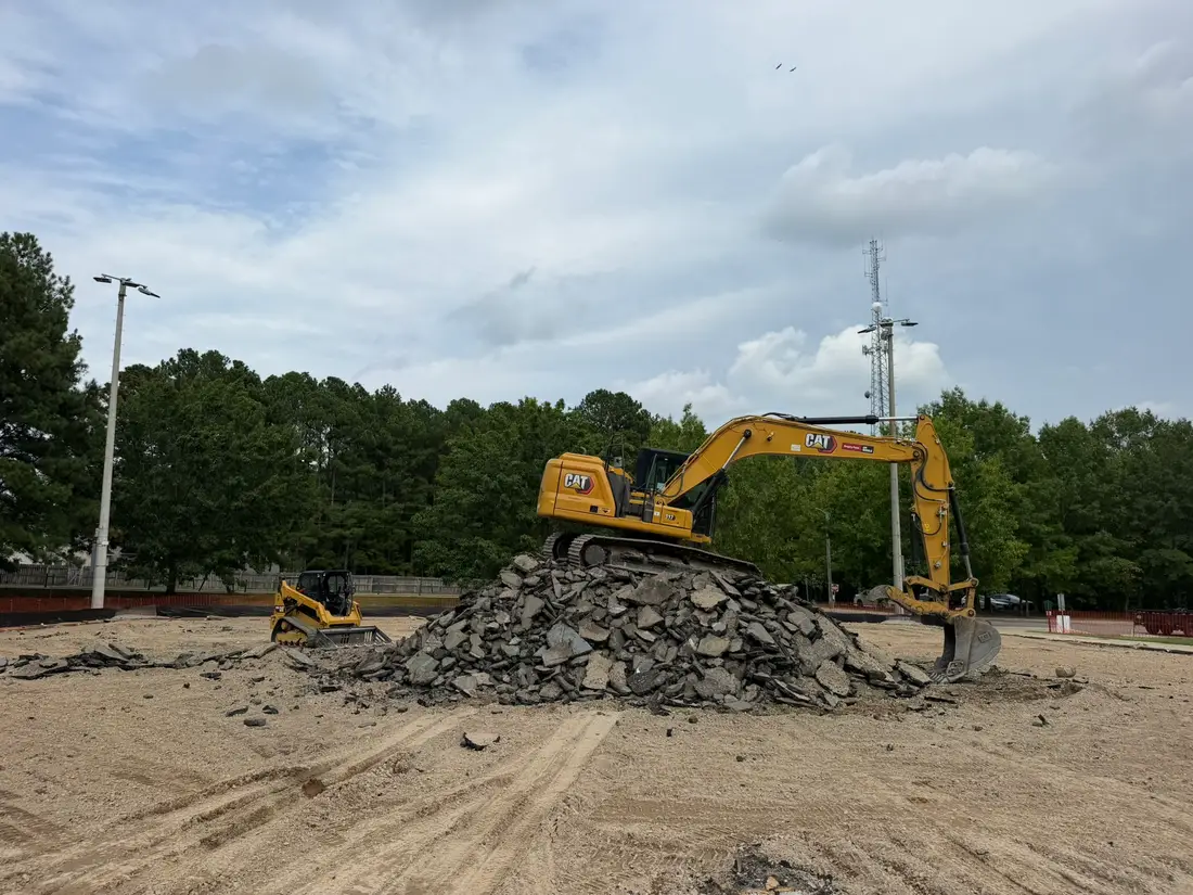 Excavator atop a pile of broken pavement during a J. Coble court demolition project