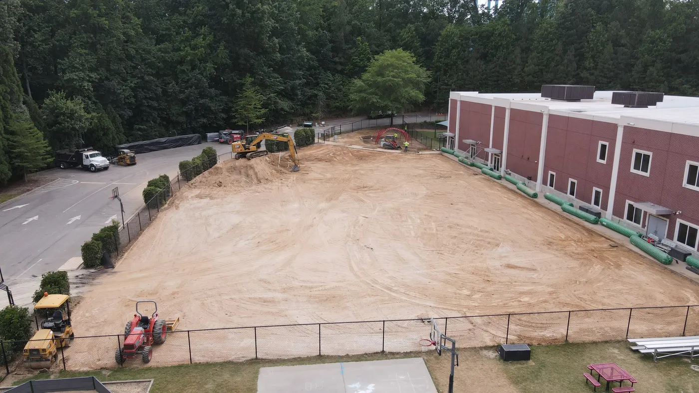 Excavator and tractor grading a large commercial lot